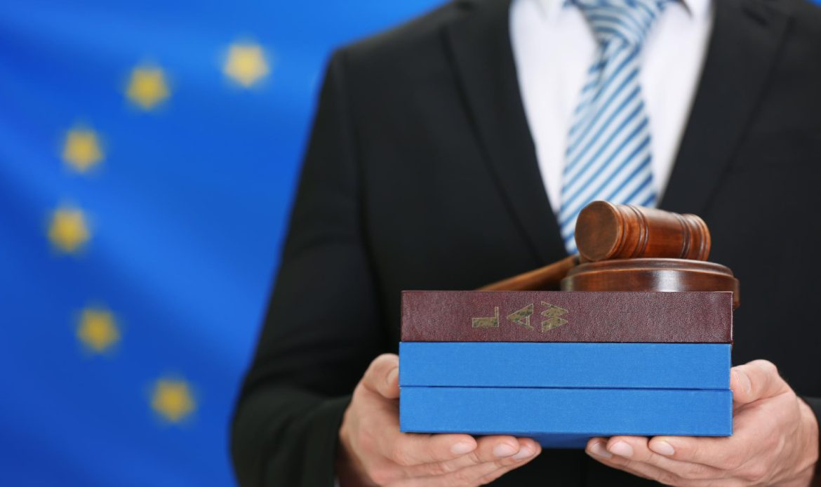 mężczyzna trzymający pudełko w ręce na tle flagii UE