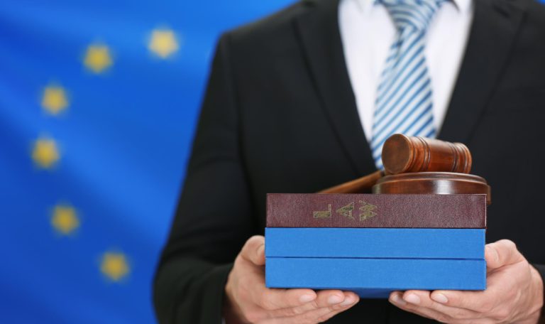 mężczyzna trzymający pudełko w ręce na tle flagii UE
