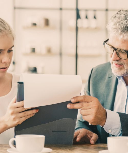 Dojrzały doradca prawny czytający dokument i wyjaśniający szczegóły młodemu klientowi